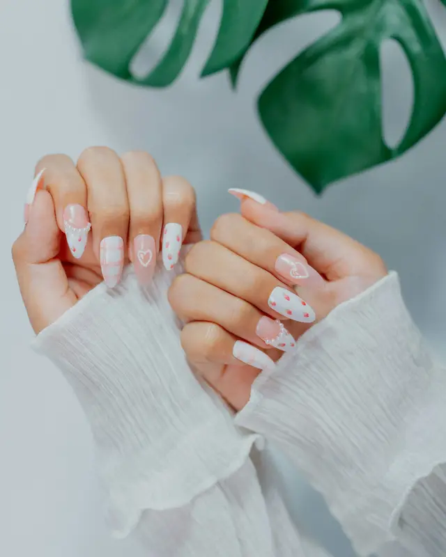 Mani con unghie bianche e rosa decorate con piccoli cuori