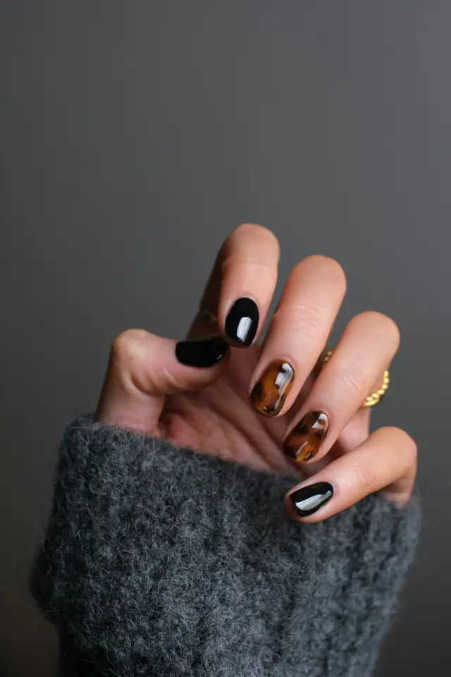 Unghie nere e color tartaruga con anello dorato